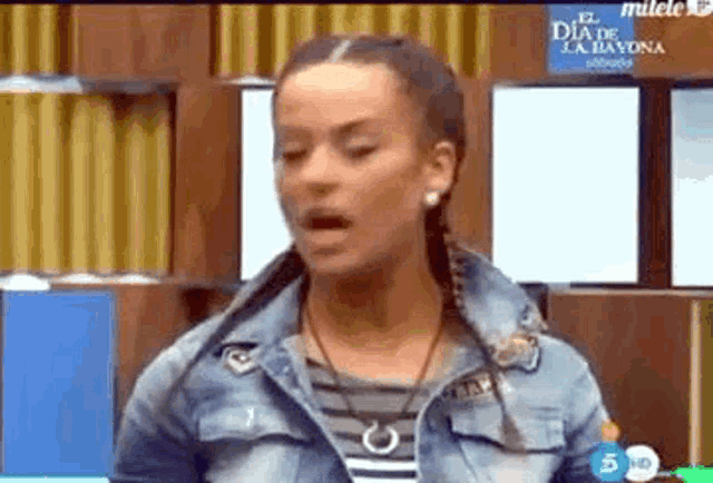 a woman in a denim jacket is making a funny face on a television screen .