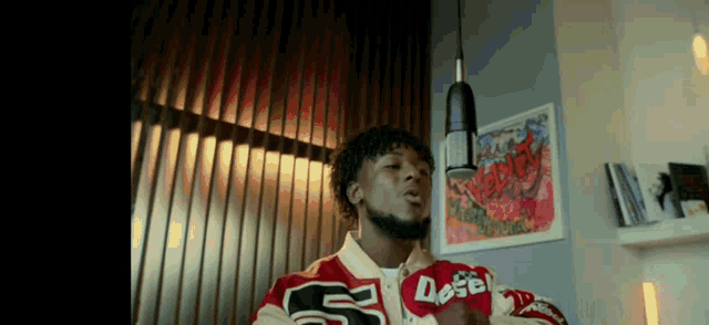 a man singing into a microphone while wearing a jacket that says dose