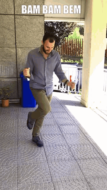 a man is dancing in front of a blue trash can with the words bam bam bem above him