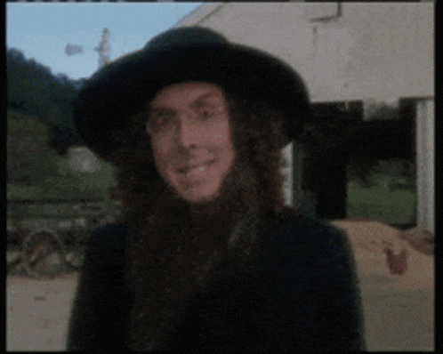a man with long hair and a beard wearing a hat