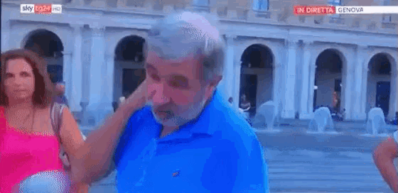 a man with a beard and a blue shirt is being interviewed by a woman in a pink tank top