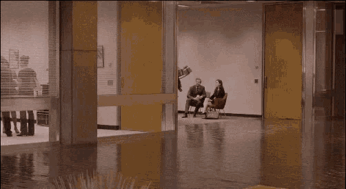 a group of people walking through a hallway with a yellow door