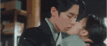 a man and a woman are kissing each other in a close up .