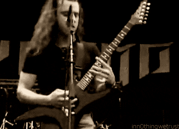 a man with long hair is playing a guitar in front of a microphone with the words innothingwetrust at the bottom
