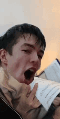 a young man with his mouth open is holding a piece of paper