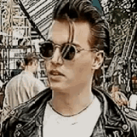 a young man wearing sunglasses and a leather jacket .
