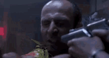 a man is pointing a gun at another man in a dark room .