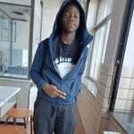 a young man wearing a hoodie is standing in front of a window in a room .