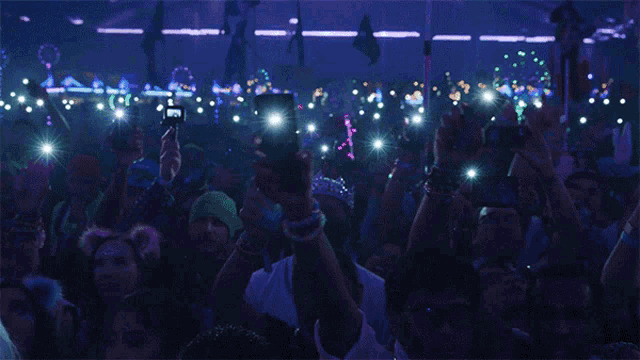 a crowd of people holding up their cell phones in the dark