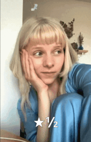 a woman with blonde hair is sitting down with her hand on her face and a 1/2 star on the bottom