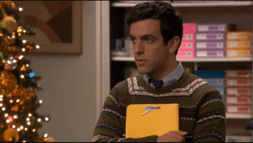 a man in a sweater and tie is holding a yellow folder with an airplane pin on it