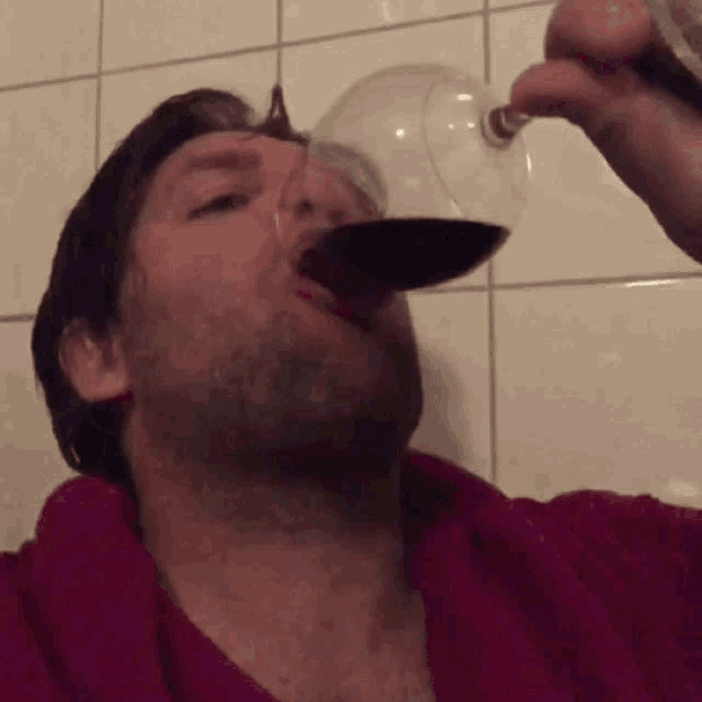 a man is drinking a glass of red wine