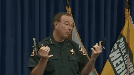 a man in a sheriff 's uniform is holding a gun in his hands