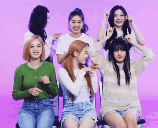 a group of young women are posing for a picture and one of them is wearing a green sweater