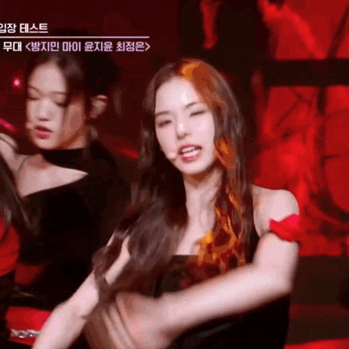 a woman in a black dress is dancing in front of a red background