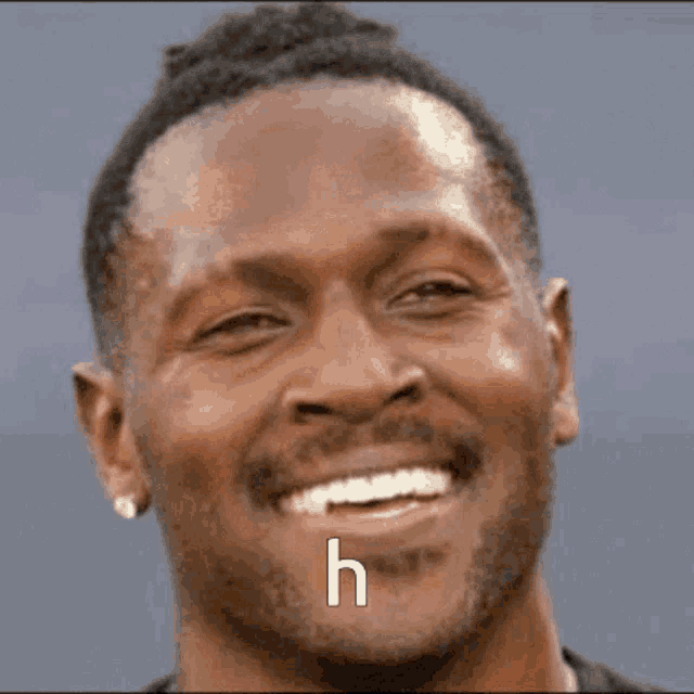 a close up of a man wearing sunglasses and smiling with the letter h above his mouth .