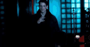 a man is smoking a cigarette in a dark room in a blurry photo .