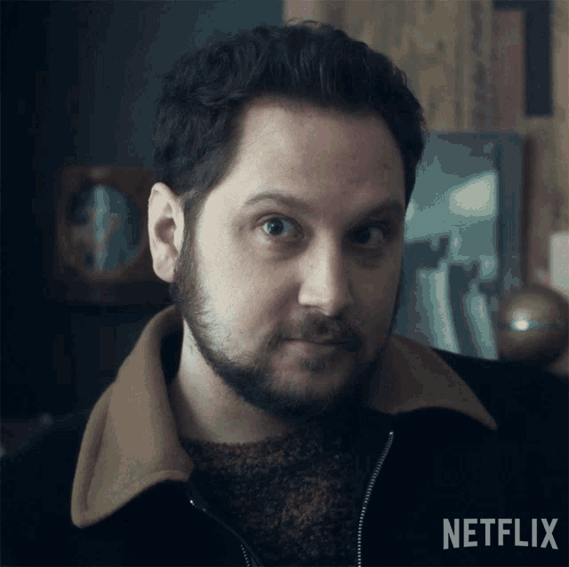 a man with a beard looks at the camera with a netflix logo in the corner