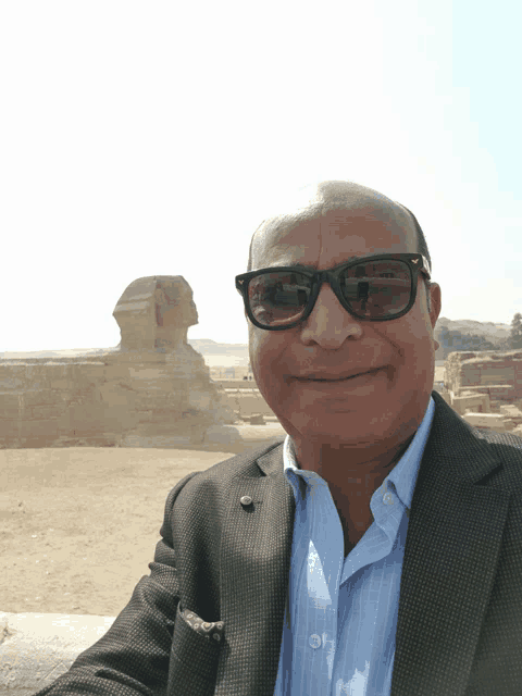 a man wearing sunglasses takes a selfie in front of a statue