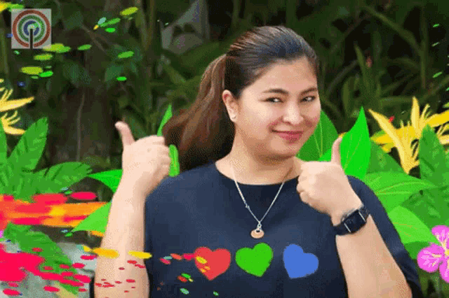 a woman in a blue shirt with hearts on it is giving two thumbs up