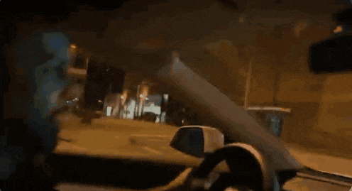 a man is driving a car at night and looking at the rear view mirror .