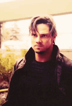 a man wearing a black jacket and black shirt looks at the camera