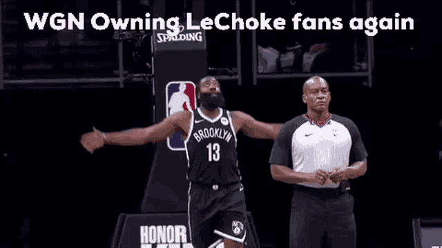 a basketball player is standing on a court with his arms outstretched and a referee standing behind him .