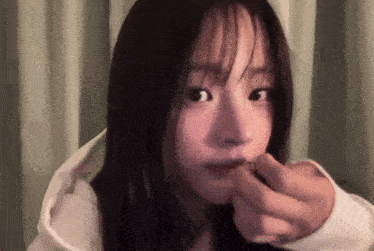 a close up of a woman 's face with her hand in her mouth