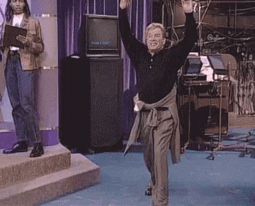 a man is dancing on a stage in front of a television in a room .