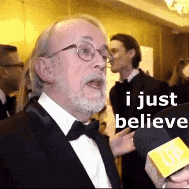 a man in a tuxedo is talking into a microphone and says i just believe