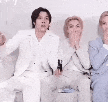 a group of men in suits are sitting on a couch .