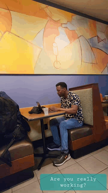 a man sits at a booth in a diner using a tablet computer