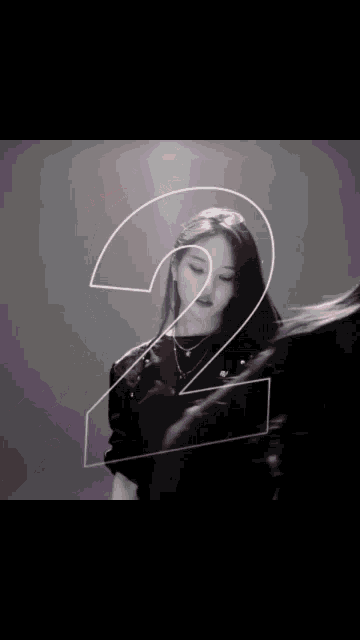 a woman is standing in front of a large number 2 .
