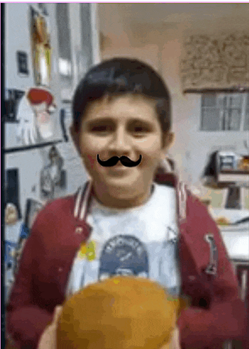 a young boy with a fake mustache is holding a pumpkin