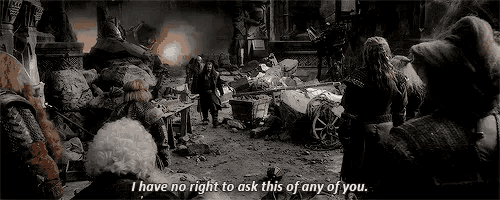 a group of people are standing around a pile of rubble and a man is standing in the middle of the room .