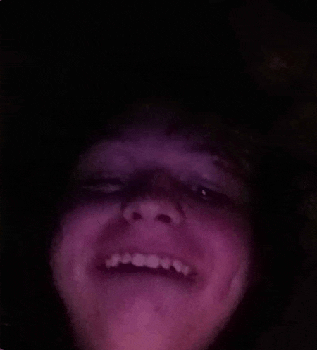 a close up of a person 's face with a purple light behind it .