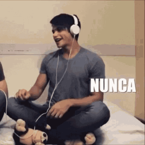 a man is sitting on a bed wearing headphones .