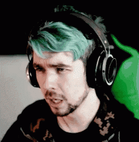 a man with green hair is wearing headphones and a black shirt .