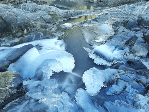 a river flowing through a rocky area with ice formations in the water