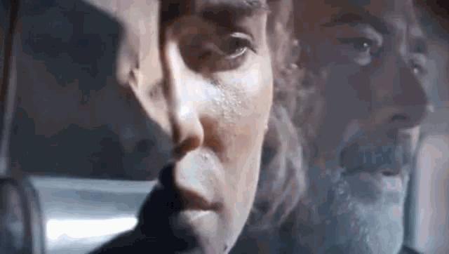 a close up of a man 's face with a shadow of another man behind him .