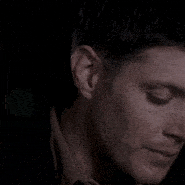 a close up of a man eating a piece of food in a dark room