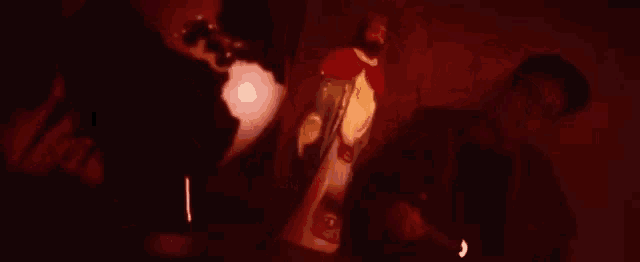 a man is standing in a dark room next to a statue of jesus and a lamp .