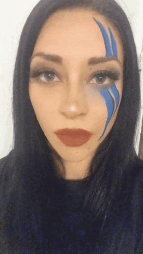 a woman with blue paint on her face is wearing red lipstick