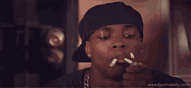 a man lighting a cigarette with the website weedporndaily.com visible in the corner