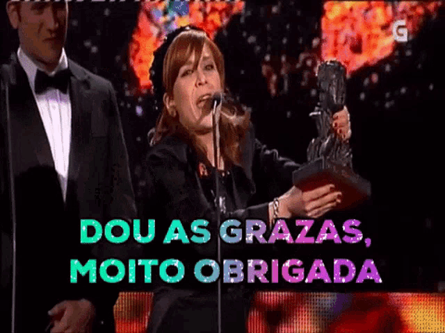 a woman singing into a microphone with the words dou as grazas moito obrigada on the bottom