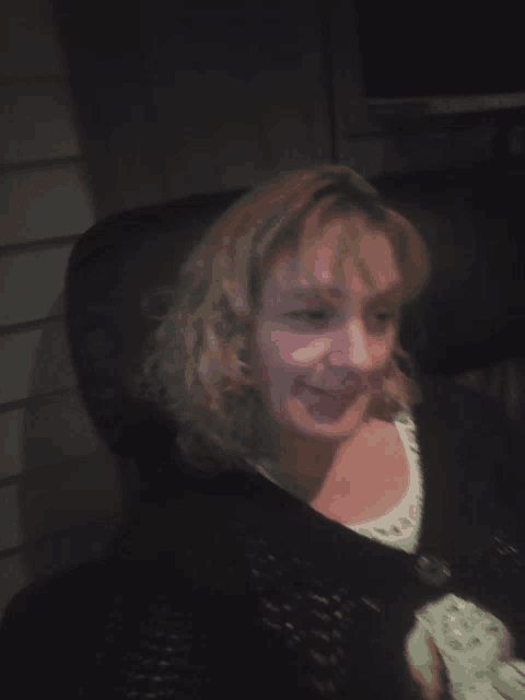 a woman wearing a black sweater and a white shirt is smiling