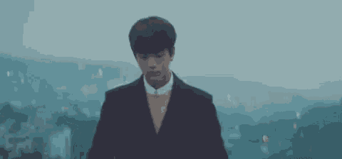 a young man in a suit and tie is standing on a rooftop in the rain .
