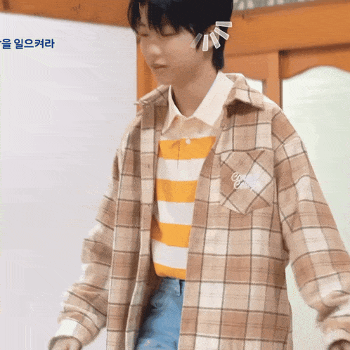 a person wearing a plaid shirt with a striped shirt underneath it