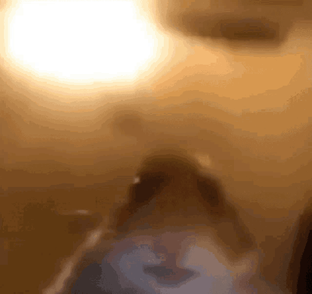 a blurry picture of a person 's face in a room with a light behind them .