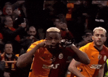a soccer player is celebrating a goal in front of a crowd of fans .
